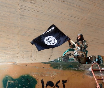 fighter of the Islamic State group waving their flag from inside a captured government fighter je
