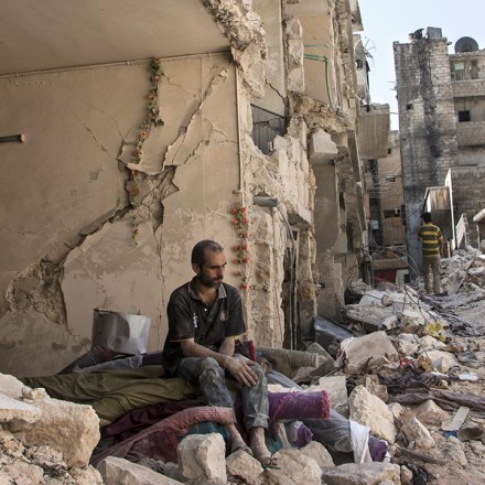 A Syrian man sits in the rubble following a barrel bomb attack the previous day in Aleppo, Syria on September 17, 2015.