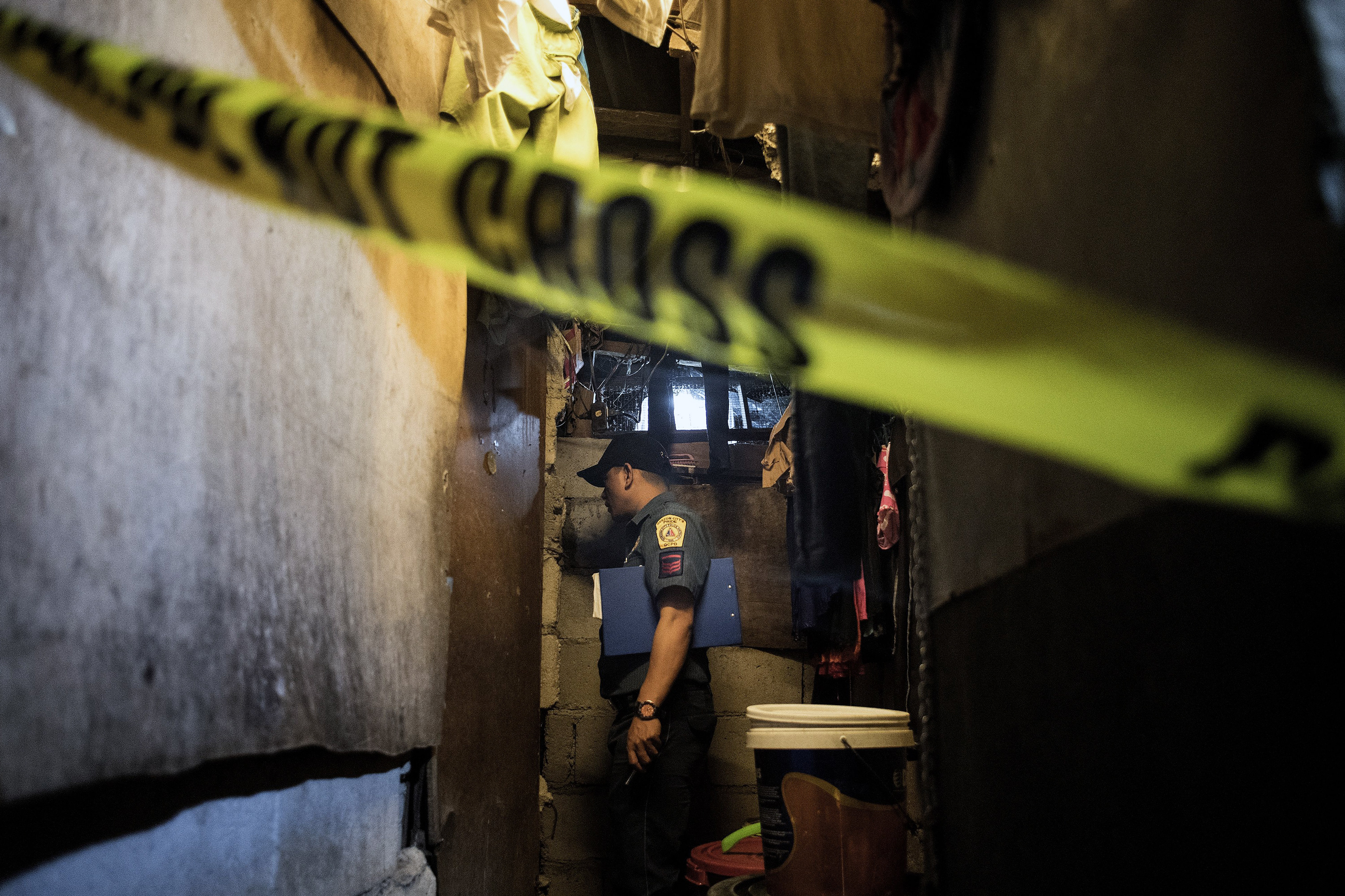 A policeman investigates the scene where the body of an alleged drug user lies dead at a slum area in Manila after unidentified assailants killed him on December 8, 2017. Philippine President Rodrigo Duterte on December 5 told human rights groups criticising his deadly anti-drug war to "go to hell" after ordering police back to the frontlines of the crackdown.  Duterte had removed the police less than two months ago in response to rising opposition to the campaign. But his spokesman said he was now reinstating them because drug crimes had risen in their absence. / AFP PHOTO / NOEL CELIS        (Photo credit should read NOEL CELIS/AFP/Getty Images)
