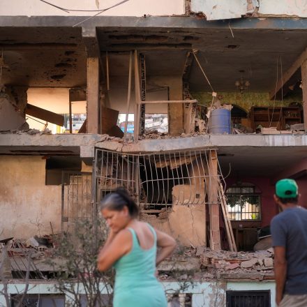 Residents look at a damaged apartment complex that neighbors say was hit during U.S. strikes to capture Venezuelan President Nicolás Maduro, in Catia La Mar, Venezuela, Sunday, Jan. 4, 2026.