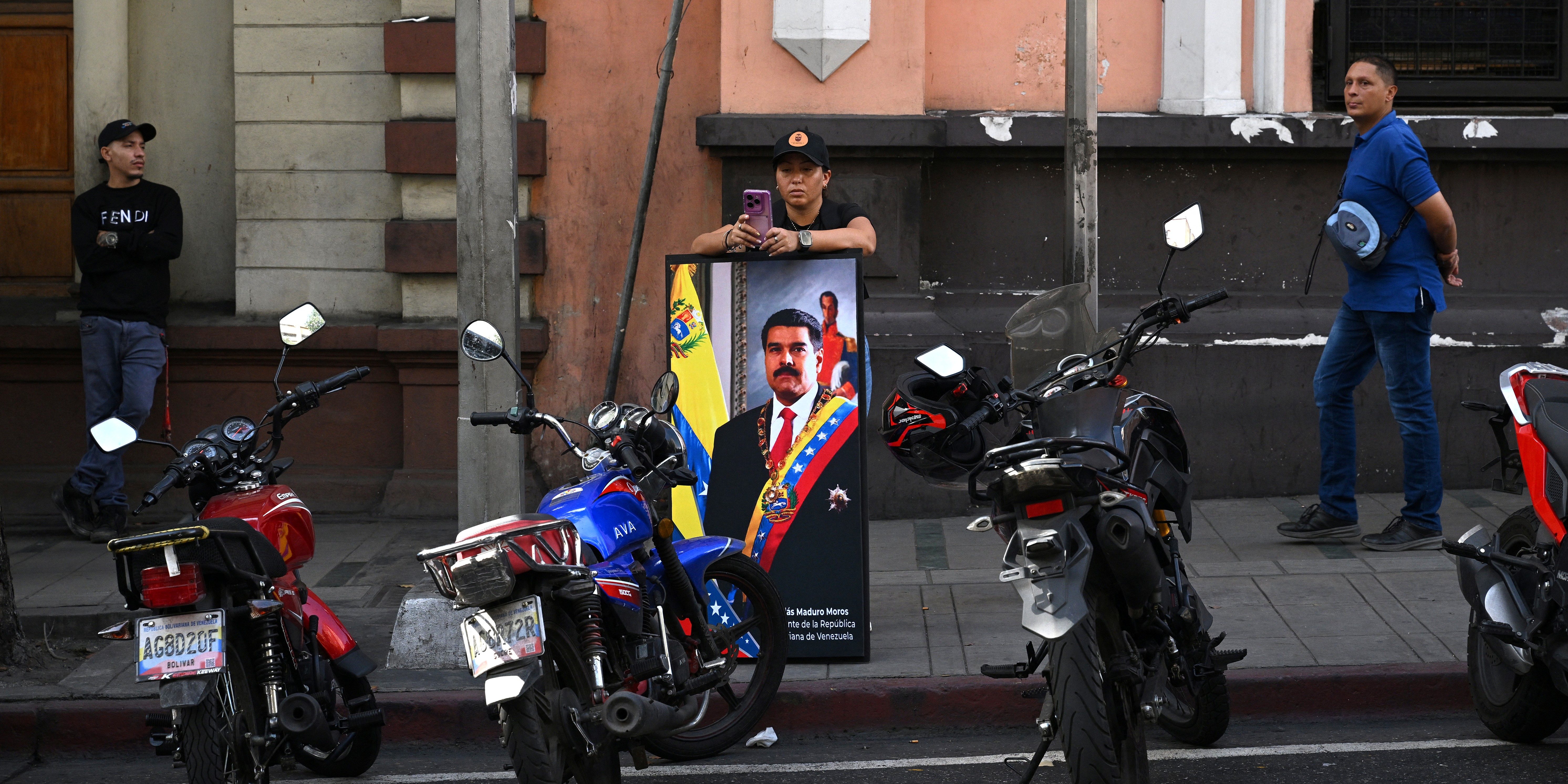 A supporter of Nicolas Maduro holds a portrait of the Venezuelan President  during a gathering near the Palacio de Miraflores in Caracas on January 3, 2026, after US forces captured Venezuelan leader Nicolas Maduro after launching a "large scale strike" on the South American country.  (Photo by Federico PARRA / AFP via Getty Images)