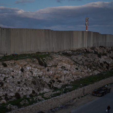 A Palestinian walks along a street next to the Israel's separation wall at dusk during the Muslim holy month of Ramadan in the West Bank town of al-Ram, Tuesday, Feb. 24, 2026. (AP Photo/Leo Correa)