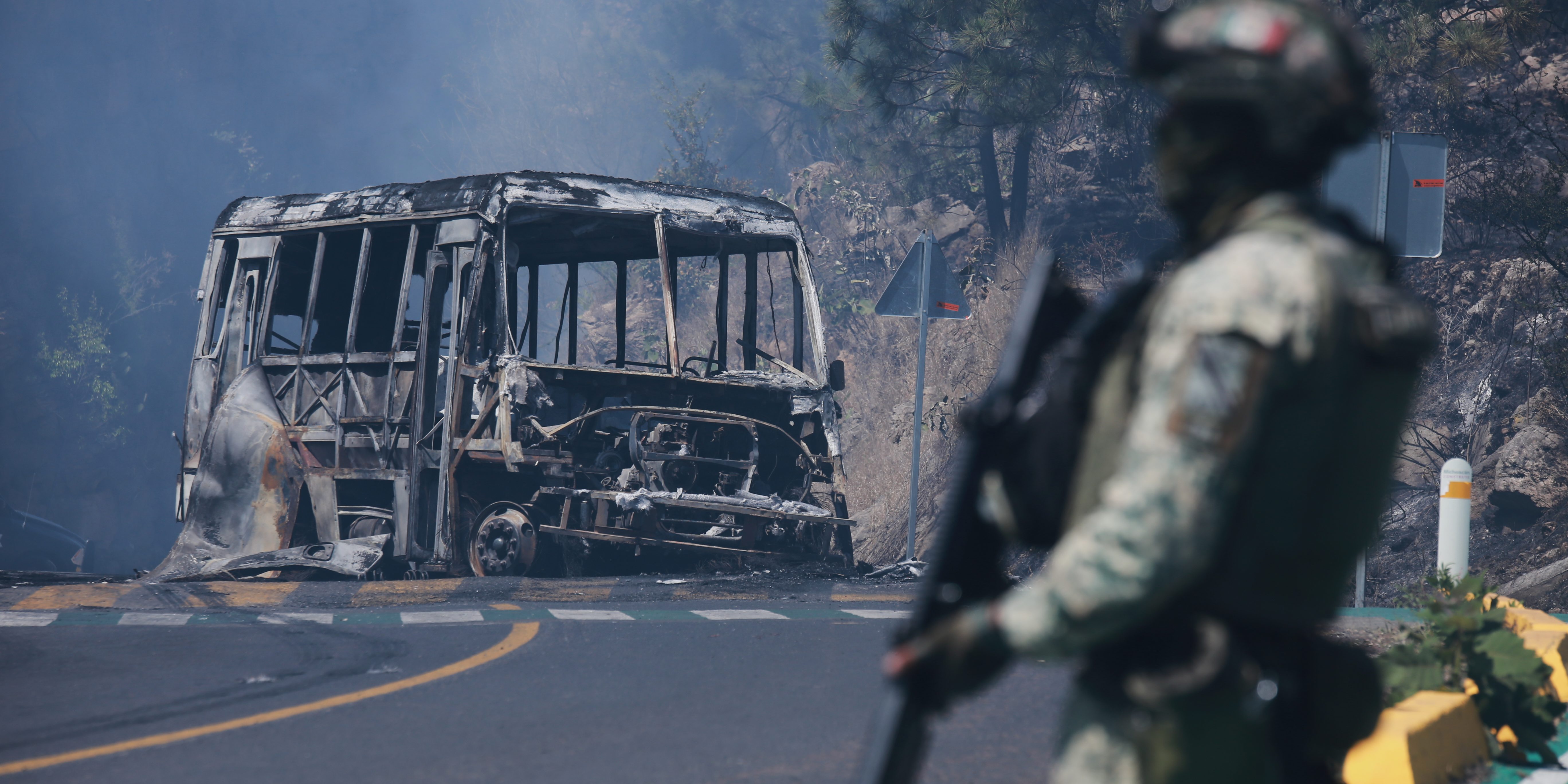 A soldier stands guard by a charred vehicle in Cointzio, Michoacán state, Mexico, Sunday, Feb. 22, 2026, following the death of the leader of the Jalisco New Generation Cartel, Nemesio Oseguera, known as "El Mencho."