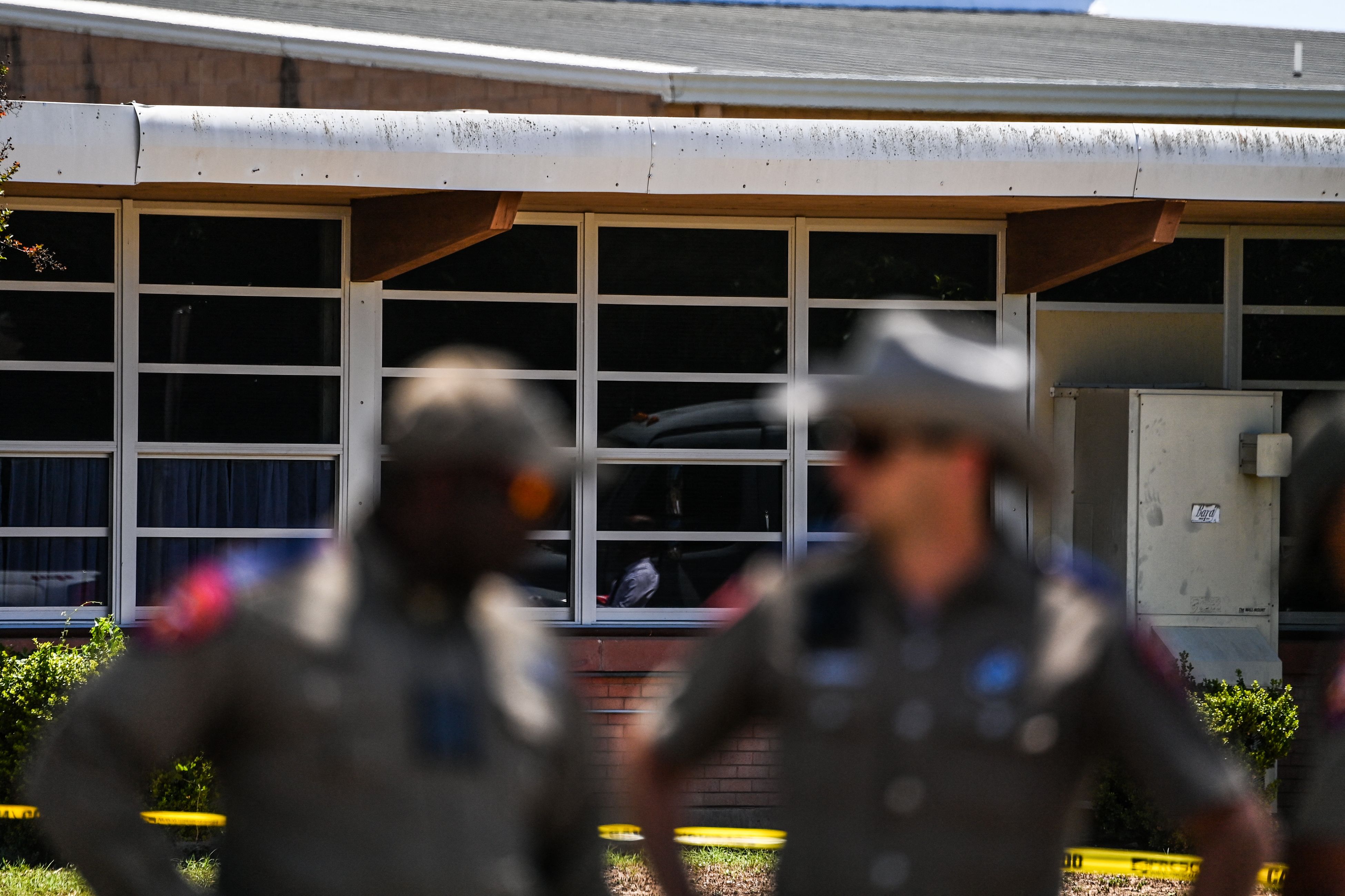 Police officers stand outside the Robb Elementary School in Uvalde, Texas, on May 25, 2022. - The tight-knit Latino community of Uvalde was wracked with grief Wednesday after a teen in body armor marched into the school and killed 19 children and two teachers, in the latest spasm of deadly gun violence in the US. (Photo by CHANDAN KHANNA / AFP) (Photo by CHANDAN KHANNA/AFP via Getty Images)