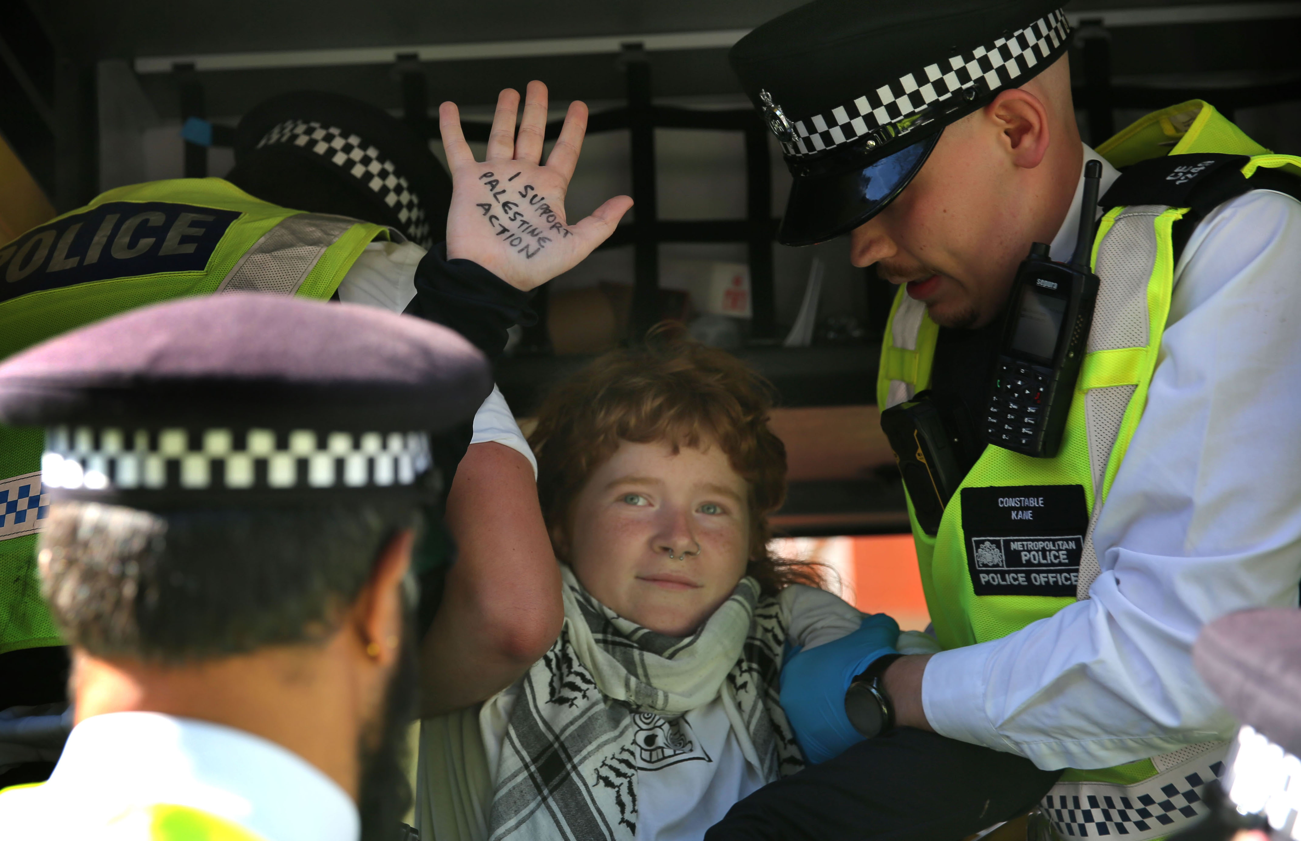 LONDON, ENGLAND - JUNE 12: A protester holds their their hand up showing the message 'I support Palestine Action' while being arrested and being put in the police transport during the demonstration at Woolwich Crown Court on June 12, 2026 in London, England. Four of "the Filton 25" activists convicted of causing over £1 million in damage to an Elbit Systems factory face potential sentencing as terrorists under Section 69 of the Sentencing Act 2020, after Mr Justice Johnson applied a "terrorist connection" to their criminal damage convictions. This controversial, post-trial mechanism subjects the pro-Palestinian activists to severe parole restrictions and long-term counter-terrorism notification requirements despite the jury not considering terrorism charges. (Photo by Martin Pope/Getty Images)