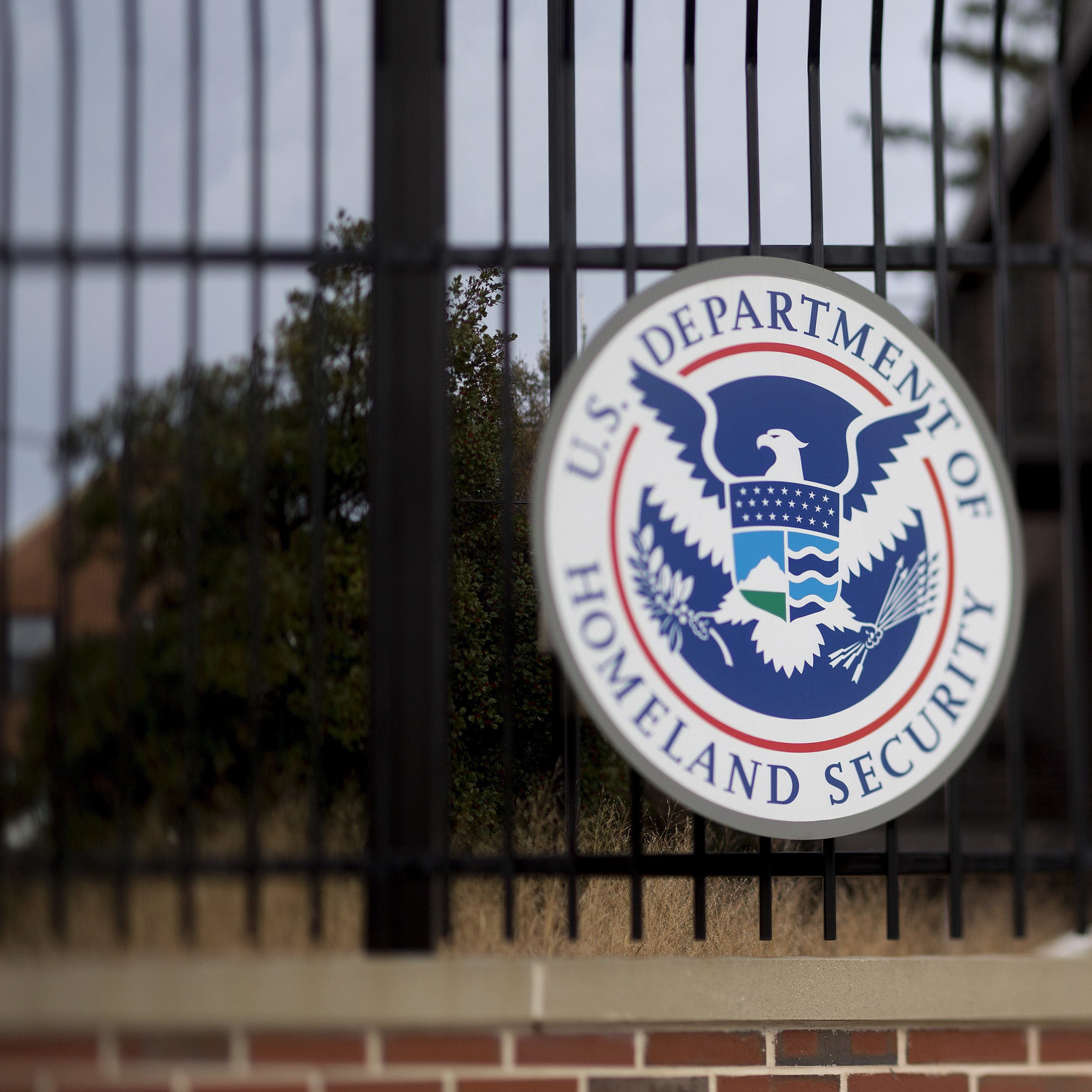 The U.S. Department of Homeland Security (DHS) seal hangs on a fence at the agency's headquarters in this photo taken with a tilt-shift lens in Washington, D.C., U.S., on Thursday, Dec. 11, 2014. The U.S. House is set to pass a $1.1 trillion spending bill that includes a banking provision opposed by many Democrats as a giveaway to large institutions. Current funding for the government ends today, and the measure would finance most of the government through September 2015. The DHS, responsible for immigration policy, would be financed only through Feb. 27. Photographer: Andrew Harrer/Bloomberg via Getty Images