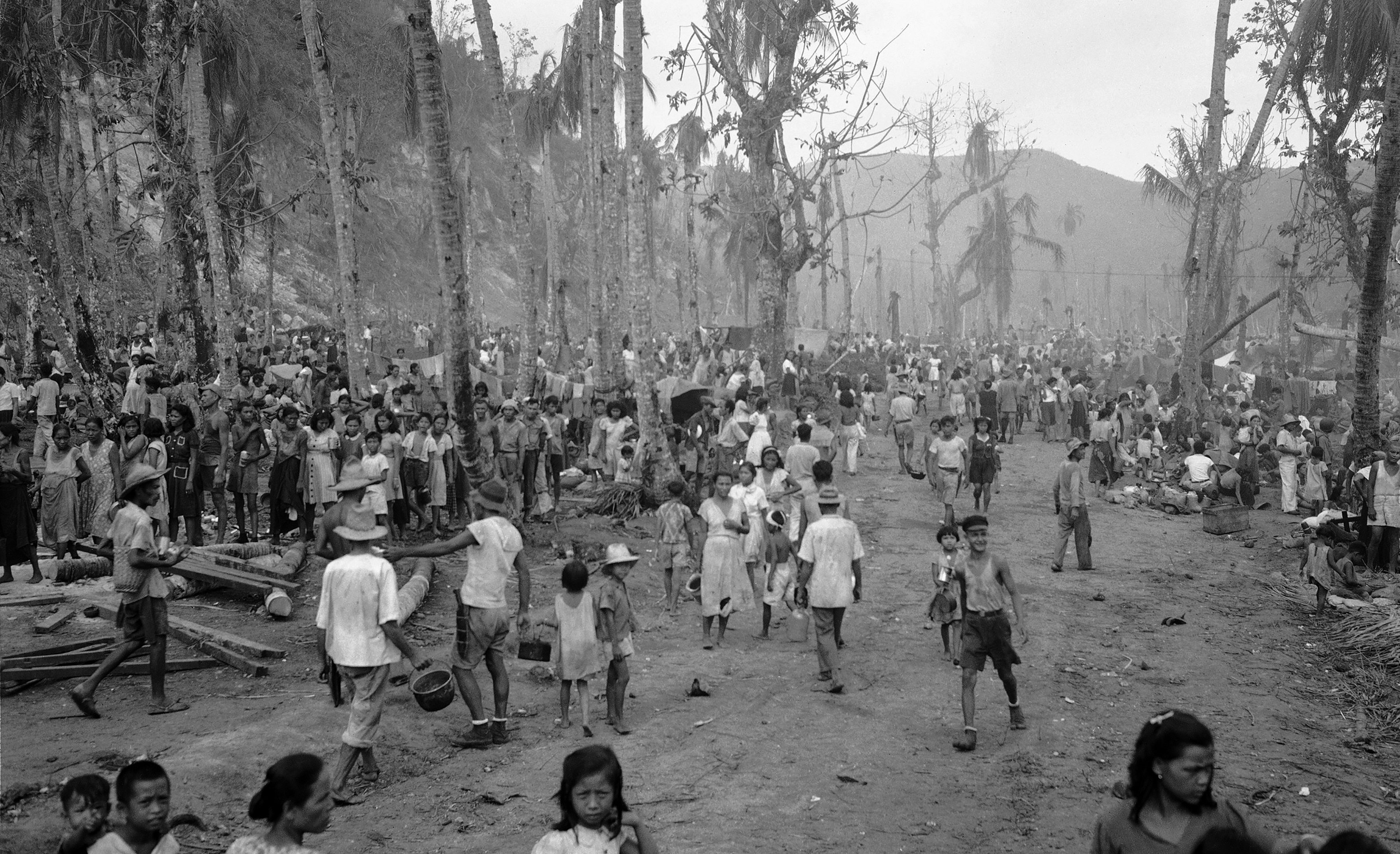 FILE - In this August, 1944 file photo, people of Guam pour out of the hills into the Agana refugee camp. The 1941 Japanese invasion of Guam, which happened on the same December day as the attack on Hawaii's Pearl Harbor, set off years of forced labor, internment, torture, rape and beheadings. More than 75 years later, thousands of people on Guam, a U.S. territory, are expecting to get long-awaited compensation for their suffering at the hands of imperial Japan during World War II. (AP Photo/Joe Rosenthal, File)