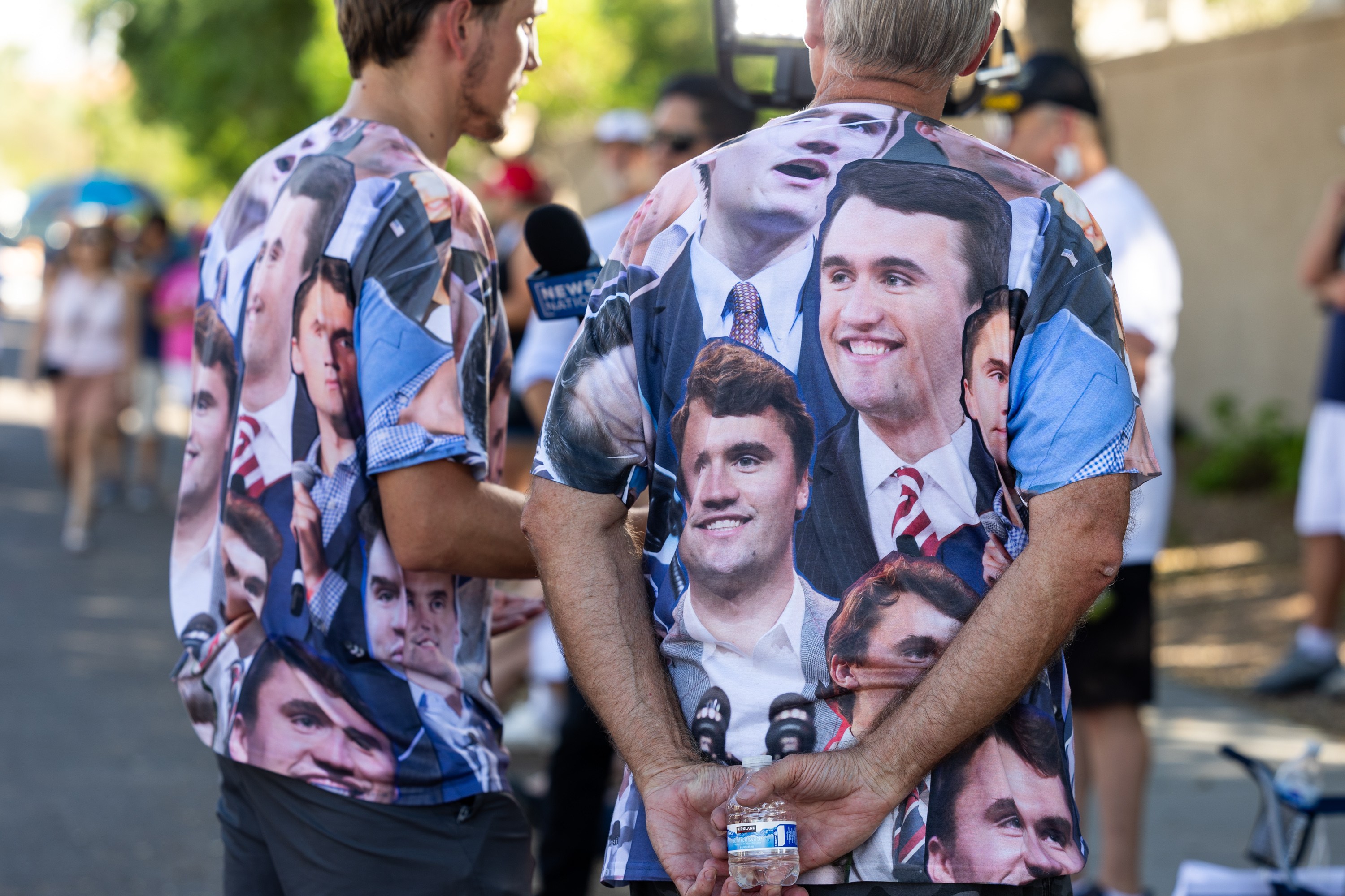 PHOENIX, ARIZONA - SEPTEMBER 20: People wearing T-shirts featuring Charlie Kirk stand outside the Turning Point USA's Phoenix headquarters to commemorate the conservative activist on September 20, 2025 in Phoenix, Arizona. As tens of thousands of people poured into Phoenix this weekend to attend Mr. Kirk's memorial service at the city's N.F.L. stadium on Sunday. (Photo by Qian Weizhong/VCG via Getty Images)