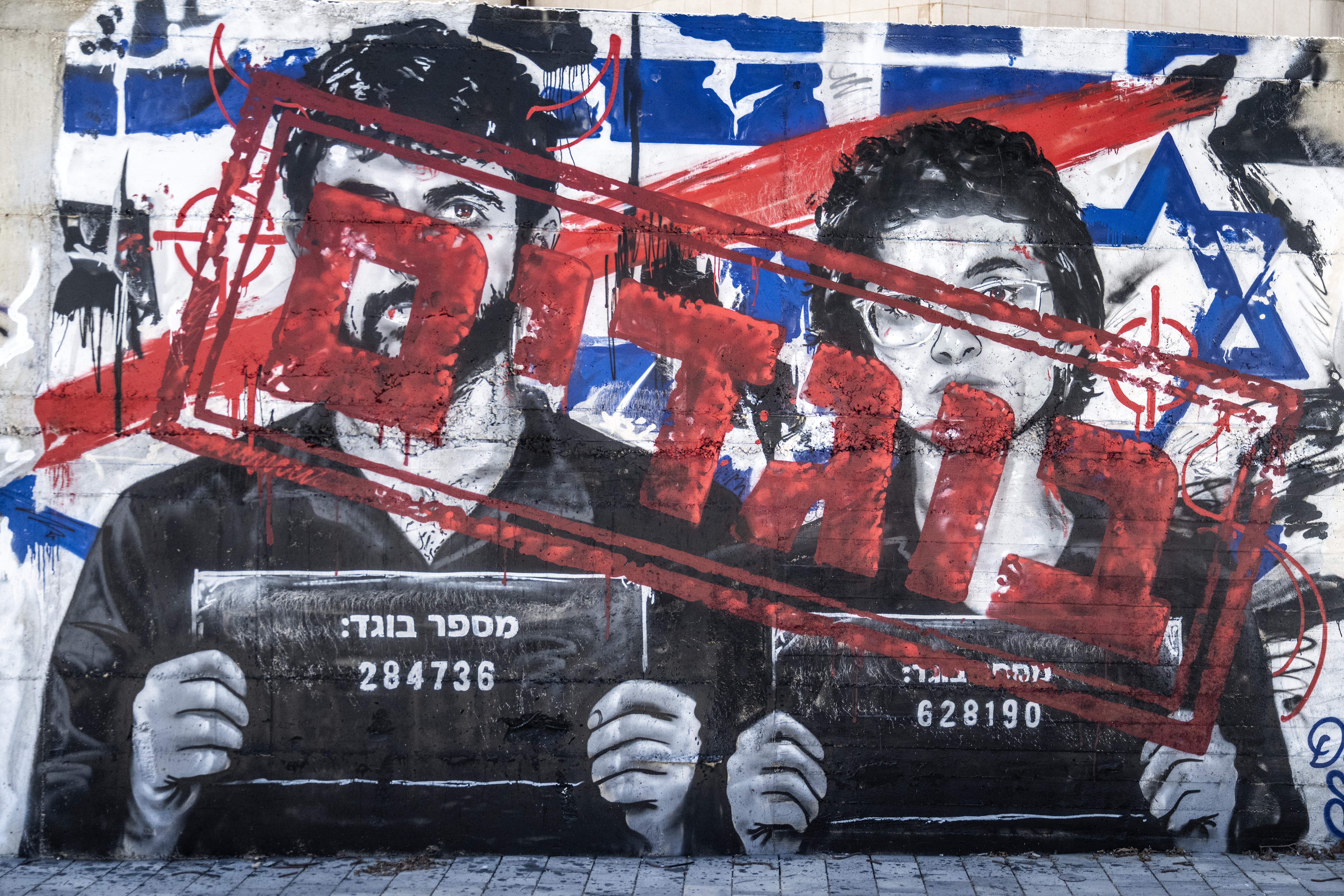 ASHDOD, ISRAEL - SEPTEMBER 16: A graffiti mural depicting Israeli filmmakers Yuval Abraham and Rachel Szor, directors of the documentary 'NAZA'- which documents civilian deaths in Gaza, features testimonies from Israeli military personnel involved in targeting and remote killing mechanisms, and frame military operations as genocide - is altered in Ashdod, Israel, on September 16, 2026. Initially painted by an artist accusing the filmmakers of being 'traitors,' the text on the mural was subsequently modified by another artist to read 'heroes.' (Photo by Mostafa Alkharouf/Anadolu via Getty Images)