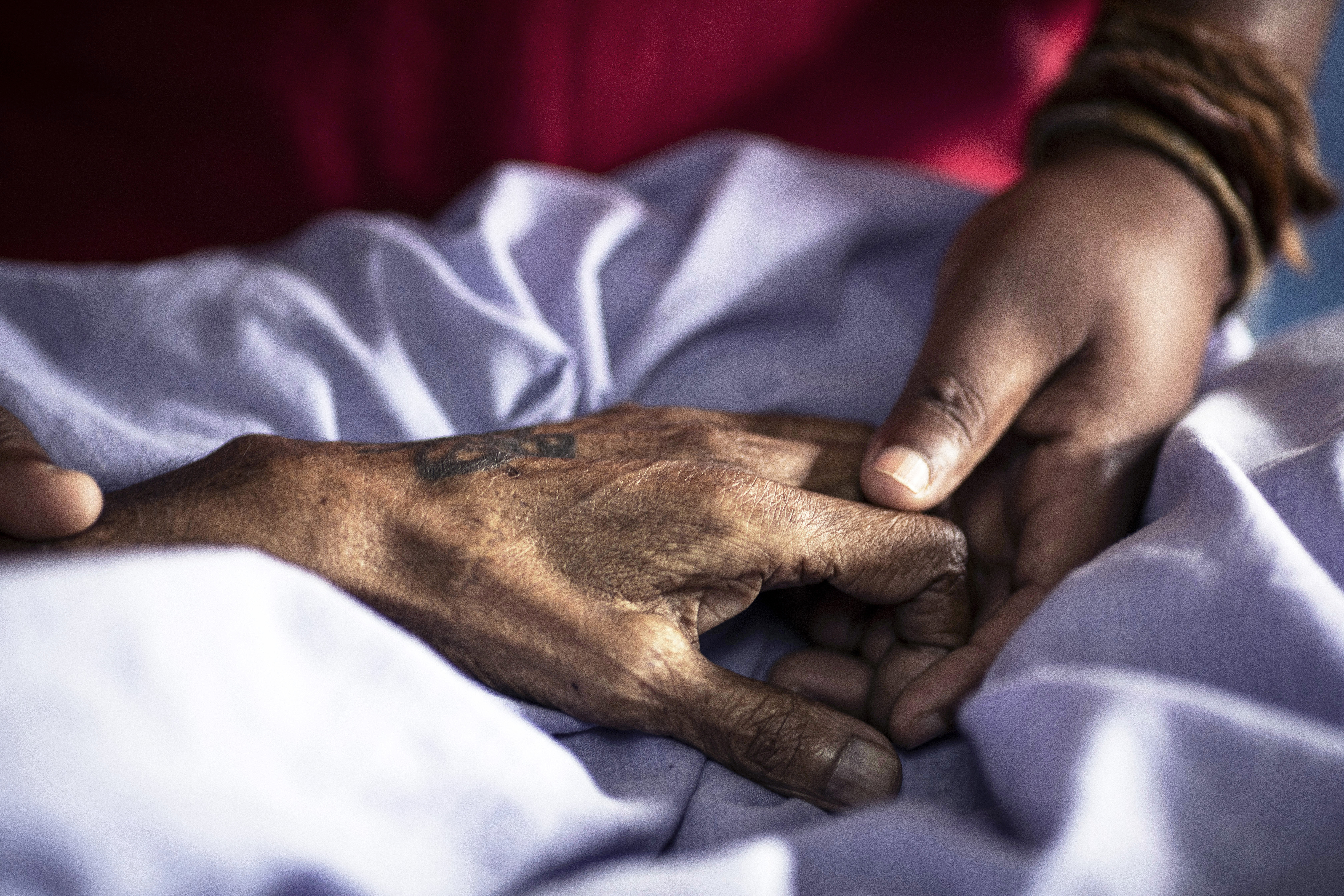 A nurse working for Hillcrest AIDS Centre comforts a patient by holding his hand in the hospice on December 1, 2025 in Hillcrest outside Durban, South Africa.